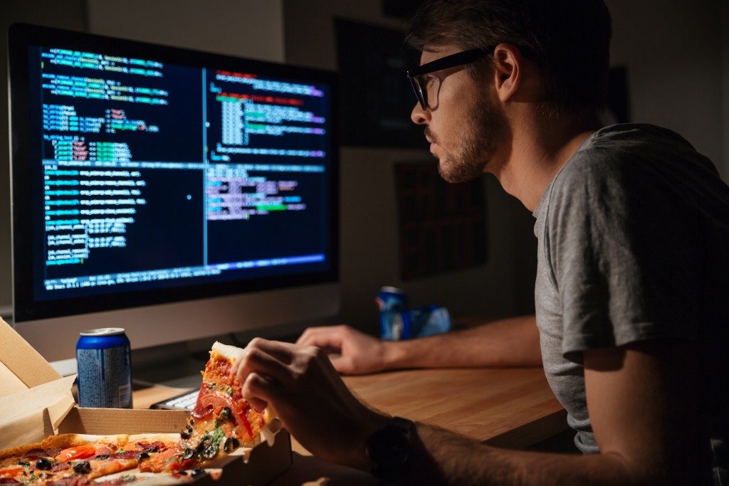 Programmer looking at codes while eating pizza