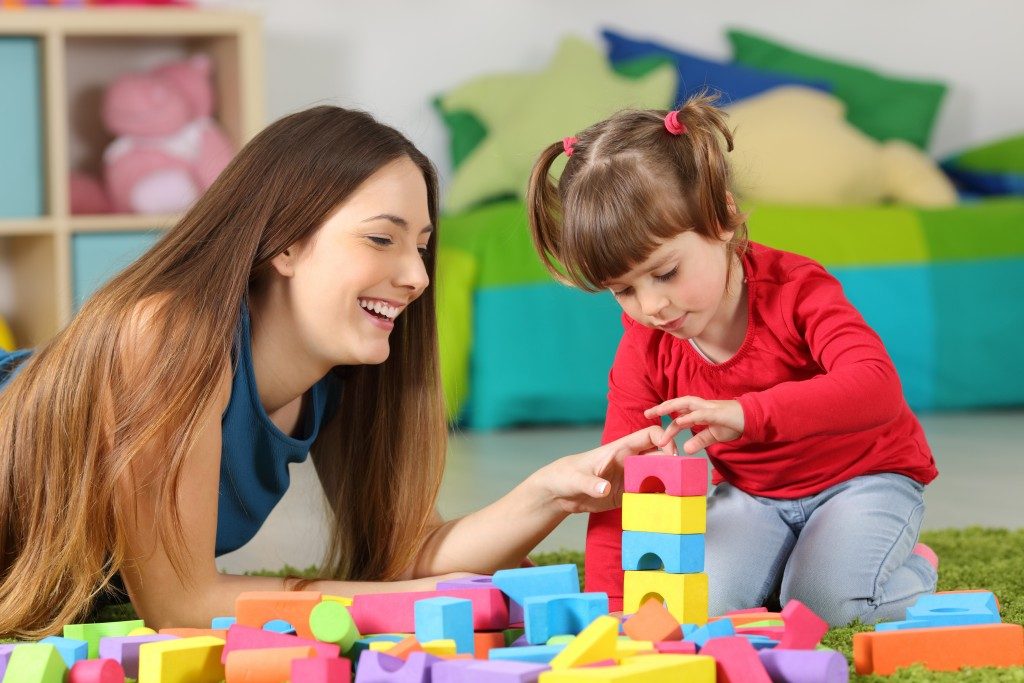 Teacher playing blocks with little girl