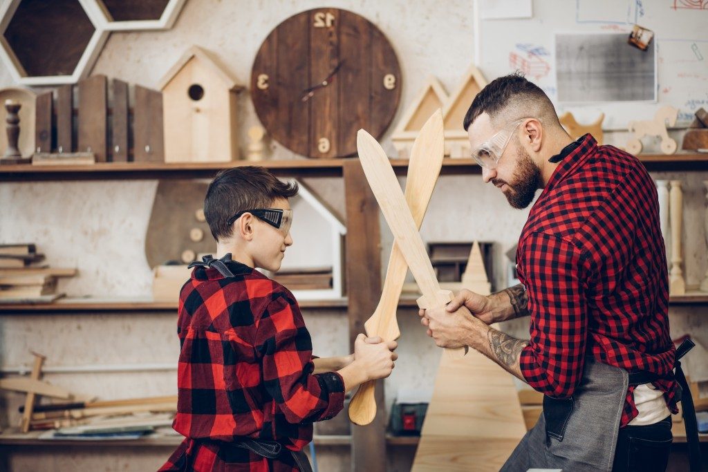 Father and child playing with handcrafted wood swords
