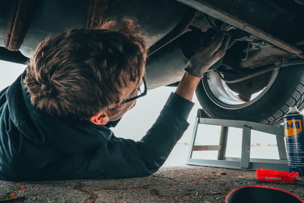 man working on the undercarriage of a car