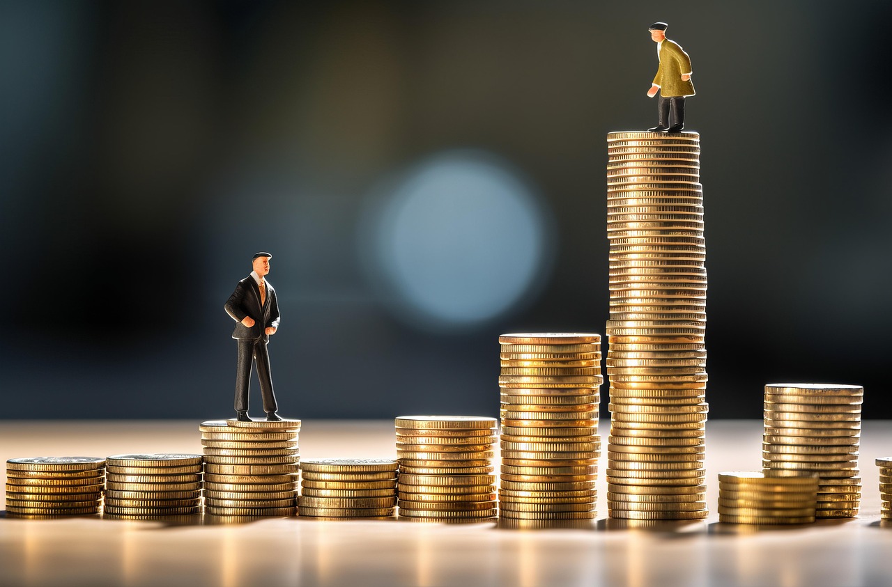 stack of coins with two miniature human toy figures in business attire