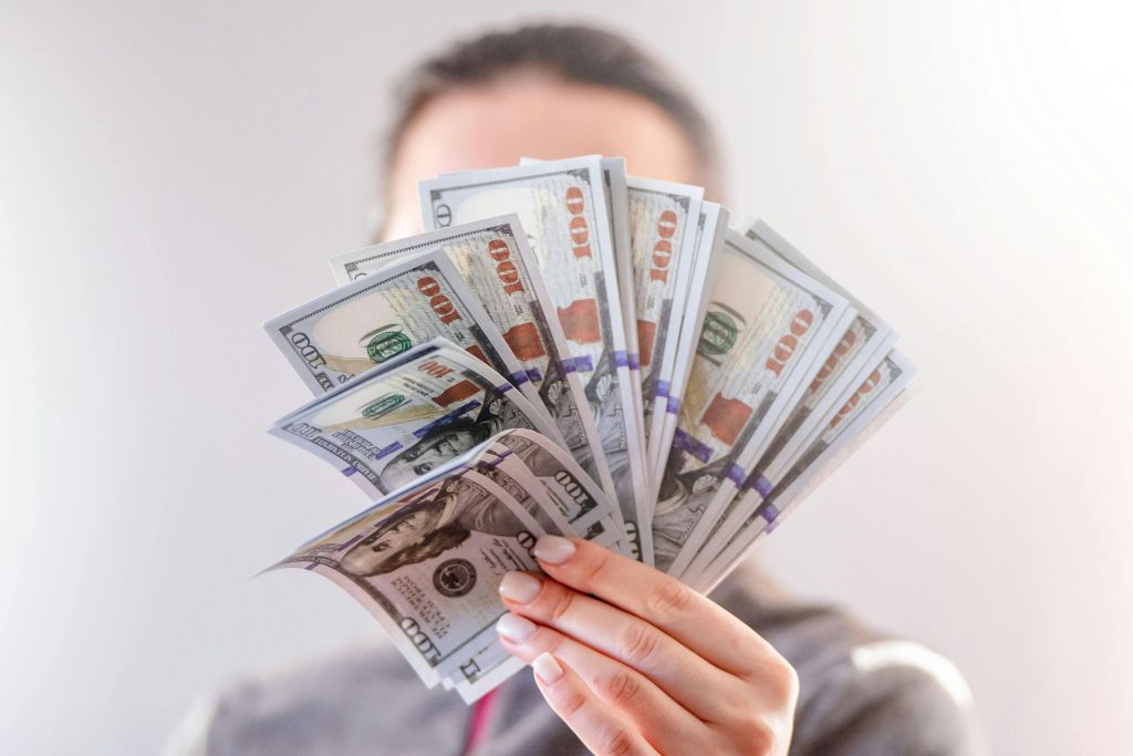 man displaying several $100 bills spread in his hand