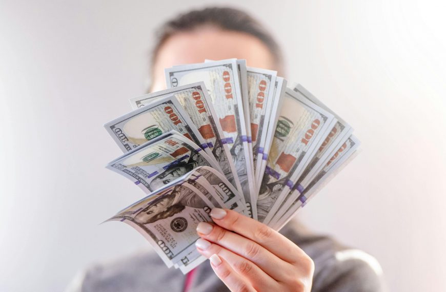 man displaying several $100 bills spread in his hand