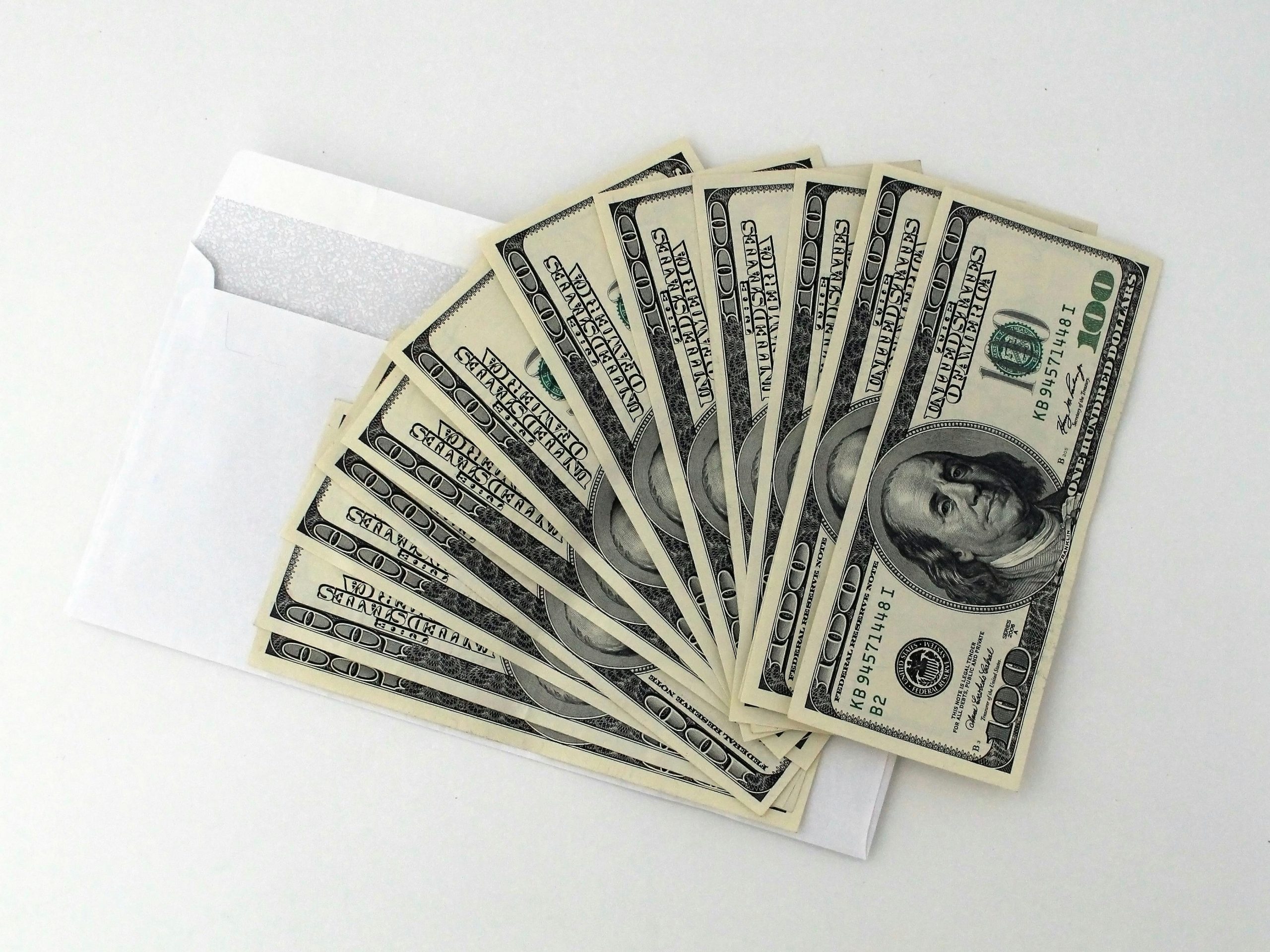 $100 bills fanned out on top of an open envelope