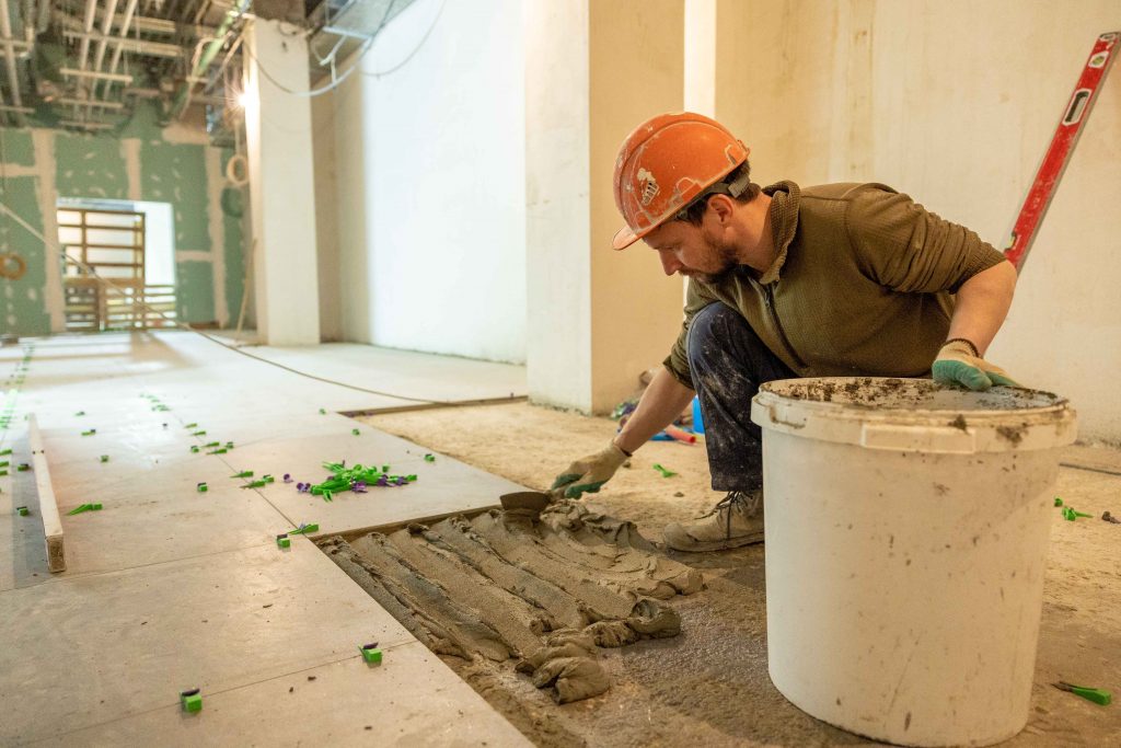 construction worker laying tiles during a retail store renovation
